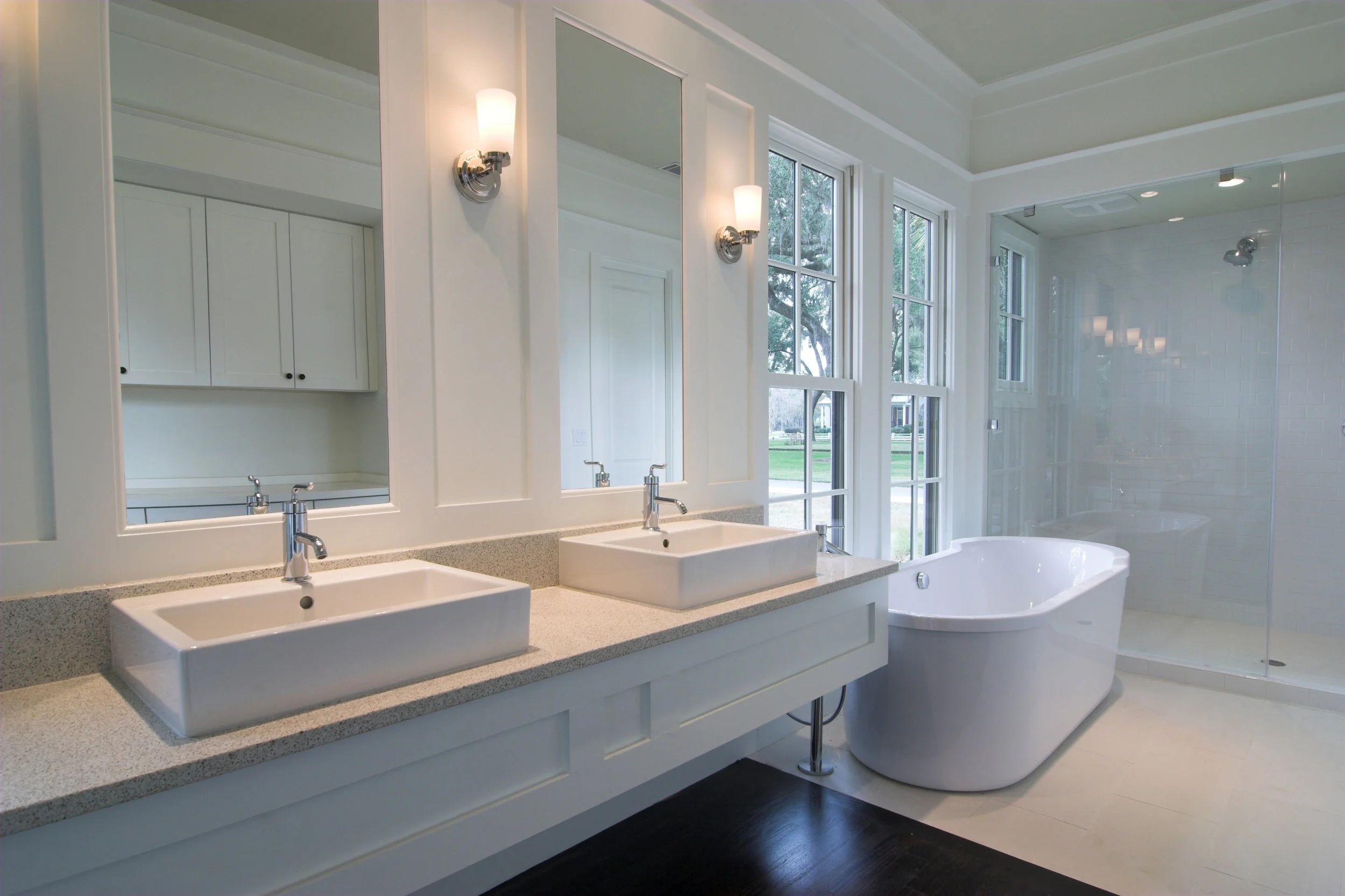 Salle de bain aux tons doux avec double lavabo et baignoire près de la fenêtre.