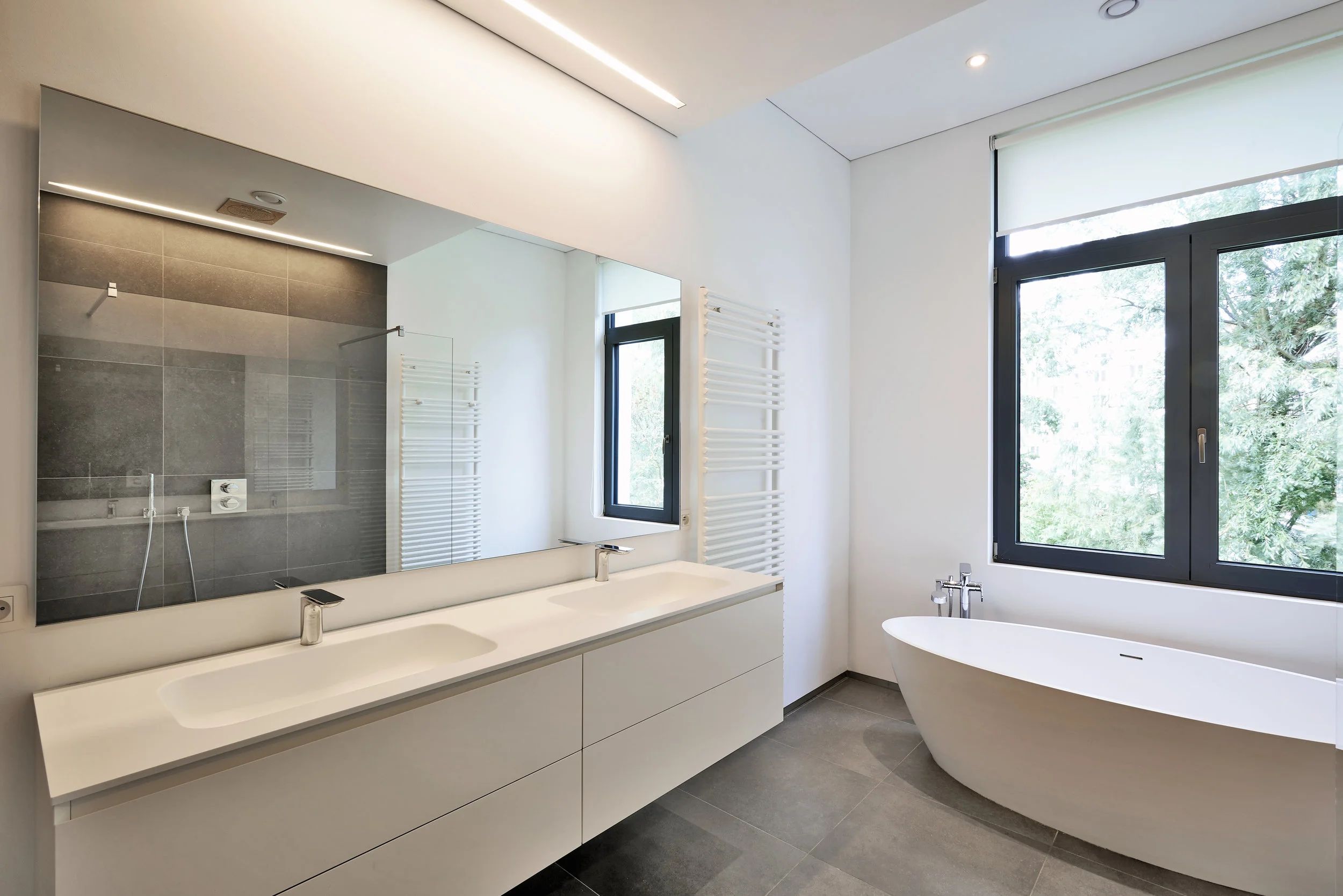 Salle de bain aux lignes épurées, vanité suspendue et baignoire autoportante.